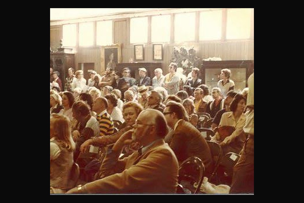 A full Abell saleroom, every chair taken, pictures hanging on the walls behind