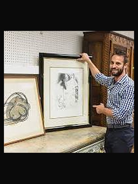 Todd Schireson holding a framed print in the gallery