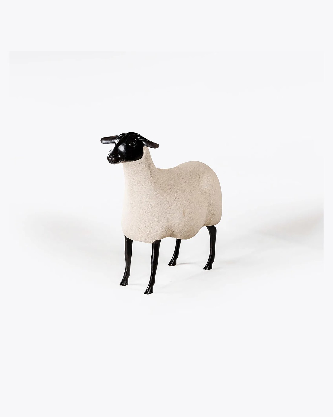 A Lalanne sheep sculpture with a patinated bronze head and legs and a pale stone-textured body