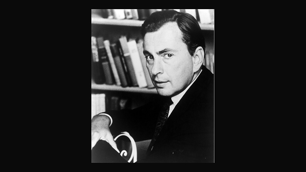 Gore Vidal seated in front of a wall of books